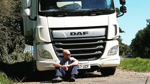 Tom Reddy Tom Reddy sat in front of a parked lorry