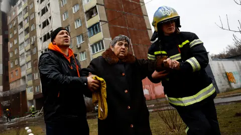 Reuters Firefighters help a woman from a building damaged during a Russian missile strike, amid Russia's attack on Ukraine, in Kyiv, Ukraine February 7, 2024