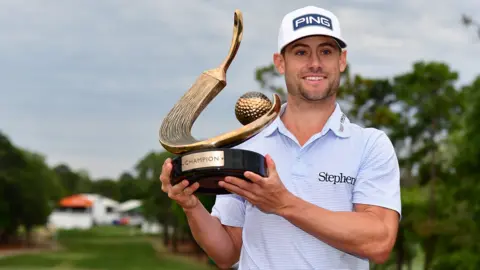 American golfer Taylor Moore smiles as he holds up the trophy for winning the Valspar Championship