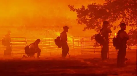 Reuters Firefighters look on as the Oak Fire burns in Darrah in Mariposa County, California, U.S. July 22, 2022.