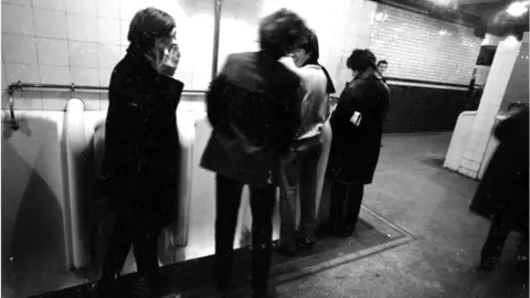 Getty Images View of members of British Rock group the Rolling Stones as they pose in the public toilets at Victoria Station, London, England, October 11, 1964. They were en route to a gig in Brighton. Pictured are, from left, Charlie Watts (1941 - 2021), Mick Jagger, Keith Richards, and Bill Wyman. (Photo by Mark and Colleen Hayward/Getty Images)