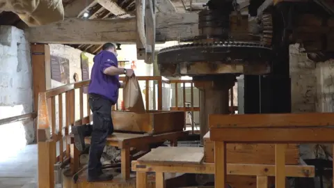 Oli Constable/BBC Simon putting in grain into the hopper