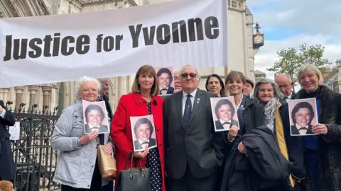 PA Media Retired police officer John Murray (centre) outside the Royal Courts of Justice in London, after he won his High Court bid