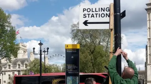 Workmen put up a sign pointing to polling stations in Westminster