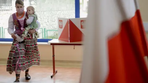 Getty Images A women and child at a polling station in Poland