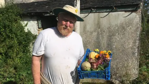 Barry George holding a crate of vegetables