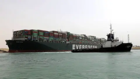 EPA A tug tries to pull the Ever Given clear from the bank of the Suez Canal (25 March 2021)