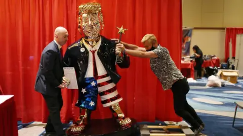 Getty Images A golden statue of Donald Trump is seen being moved into CPAC conference