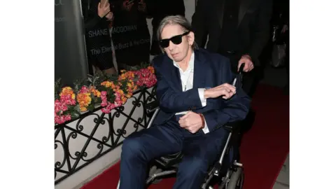 Ricky Vigil M Shane MacGowan in a wheelchair