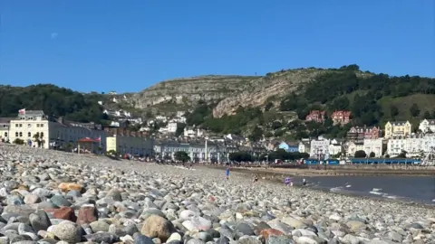 BBC Llandudno's North Shore Beach covered in pebbles with the promenade in the background