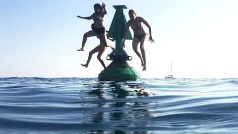 AFP Swimmers jump off a buoy into the sea in Nice, south-eastern France, on 6 August 2018,