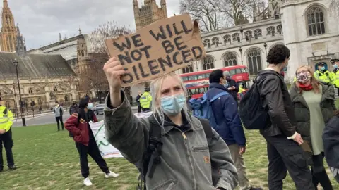 BBC A woman is pictured holding a banner at a vigil for Sarah Everard in Parliament Square on Monday