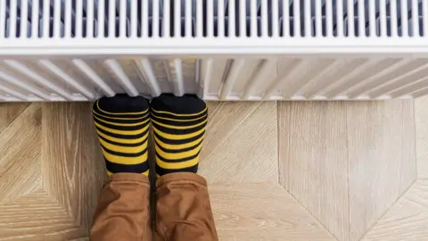 Getty Images A person rests their feet against a radiator