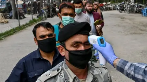 AFP In this file photo taken on April 24, 2020 a health worker (R) checks the body temperature of a devotee as a preventive measure against the COVID-19 coronavirus before the Friday prayers on the first day of the Muslim holy month of Ramadan at Wazir Akbar Khan mosque in Kabul.