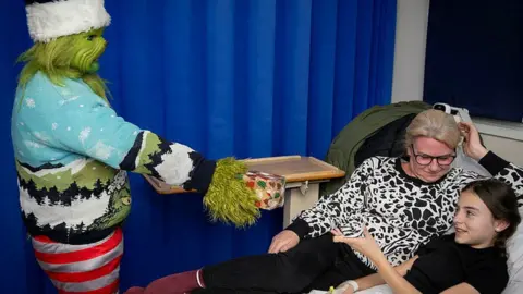 Royal Wolverhampton NHS Trust The Grinch handing a girl a present