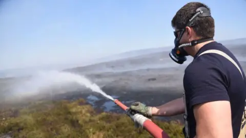 Greater Manchester Fire and Rescue Service Firefighter tackles the blaze