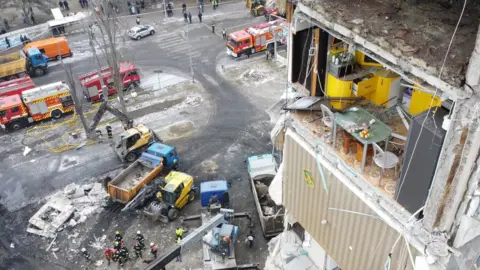 Yan Dobronosov Wide shot of the kitchen with rescue vehicles seen on the street below