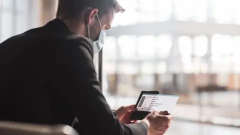 Getty Images Man looking at phone in airport