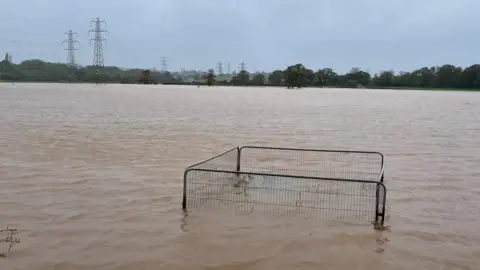 PA Media Flood water covers a field after the River Clyst overflowed in Clyst Saint Mary, near Exeter.