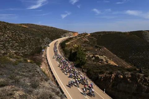 Tim de Waele / Getty Images A general view of the peloton passing through a landscape