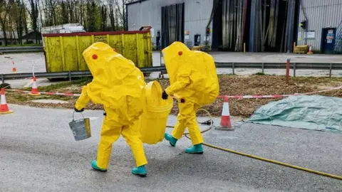 Liskeard Community Fire Station Men in hazard suits getting rid of hazardous waste from bin