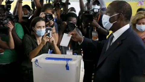 EPA Ivory Coast President Alassane Ouattara (R) casts his vote at a polling station during the first round of the presidential election, in Abidjan, Ivory Coast, 31 October 2020.