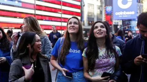 Reuters Employees of Coinbase Global Inc, the biggest U.S. cryptocurrency exchange, watch as their listing is displayed on the Nasdaq MarketSite jumbotron at Times Square in New York, U.S., April 14, 2021