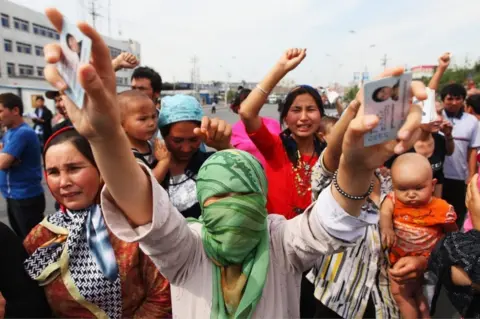 Getty Images An Uighur woman holds the IDs of her relatives who are currently detained, as she and others protest on a street in July, 2009
