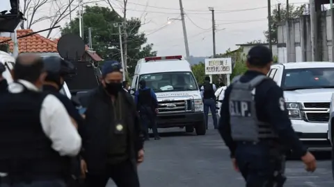 Reuters An ambulance is surrounded by police officers at a crime scene where gunmen killed at least 13 Mexican police officers in an ambush, in Coatepec Harinas, Mexico March 18, 2021