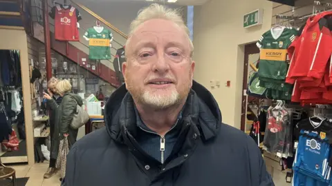 Paul McCartan stands in his shop