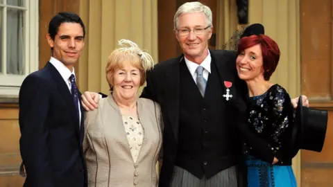 PA Media Paul O'Grady with his MBE medal, alongside his partner Andre Portasio, sister Sheila Rudd and daughter Sharyn Mousley