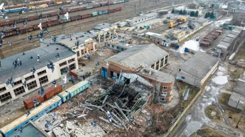 Getty Images Damaged buildings and disused trains pictured in a rail yard in Lyman, Ukraine