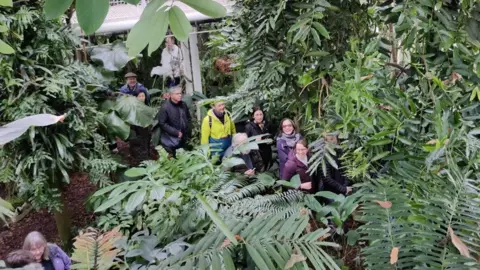 CUBG People in a glasshouse looking at a flower