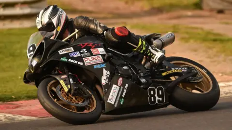 Chris Ganley/Colin Port Images Motorcyclist Chris Ganley racing his bike, leaning into a corner on a racetrack