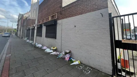 Kevin Shoesmith/BBC Floral tributes in front of Legacy's premises in Hessle Road, Hull