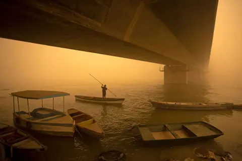 Hussein Faleh / AFP A fisherman paddles his boat during a sandstorm in Iraq's southern city of Basra