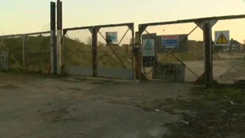 BBC Locked gates across a waste land