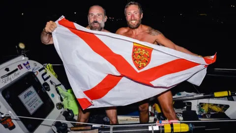 Atlantic Campaigns Rowers Steve Hayes and Peter Wright holding Jersey flag