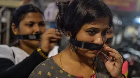 AFP Supporters of Bharatiya Janata Party (BJP) cover their mouths with black fabric as they participate in a candle-lit procession calling for justice following the recent rape and murder of a 27-year-old veterinarian