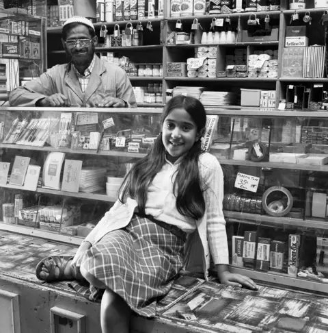 Photograph by David Goldblatt, Ozzie Docrat with his daughter Nassima in his shop before its destruction in 1977.