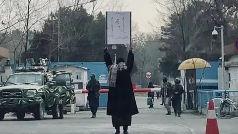 A woman protesting the Taliban's ban on education alone in front of Kabul University. Published on social media and shared with the BBC