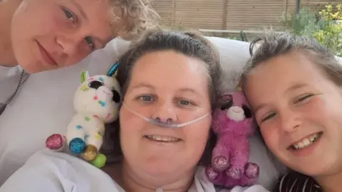 Louise Evans Louise Evans in bed at Stoke Mandeville Hospital with her two children visiting