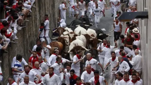 EPA Runners try to avoid bulls of the Puerto de San Lorenzo bull ranch as they run down a street during the traditional San Fermin bull run