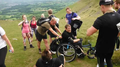 Family photo Jamie in a wheelchair with a group on a mountain