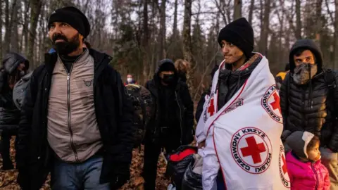 Getty Images A Kurdish family from Dohuk in Iraq is assisted by activists from the NGO Grupa Granica (Border Group) on 9 November