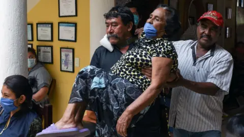 AFP Relatives carry a woman with symptoms of Covid-19 in Chiapas state