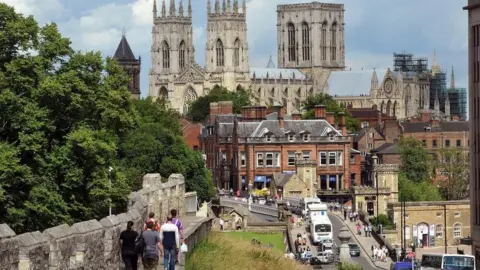 Jeff Overs/BBC York Minster, people walking on city walls and traffic