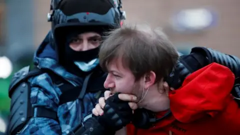 Reuters A law enforcement officer detains a man while holding him by the face in Moscow