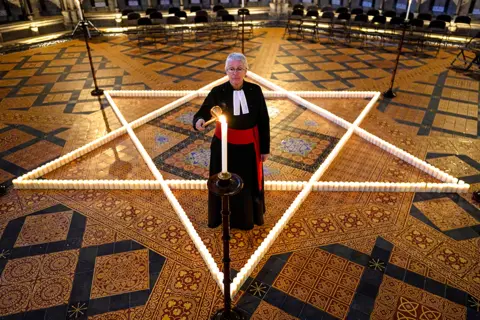 Ian Forsyth / Getty Images On Wednesday in York, England, the Reverend Canon Maggie McLean, Canon Missioner at York Minster lit one of 600 candles shaped as a Star of David on the floor of the Chapter House of York Minster on 25 January 2023