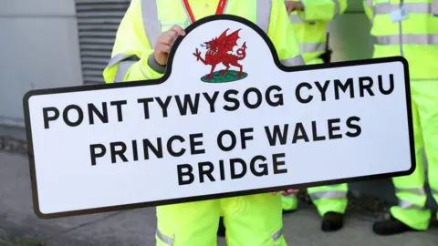 WPA Pool/Getty Images Maintenance worker holds up a sign for the Prince of Wales Bridge